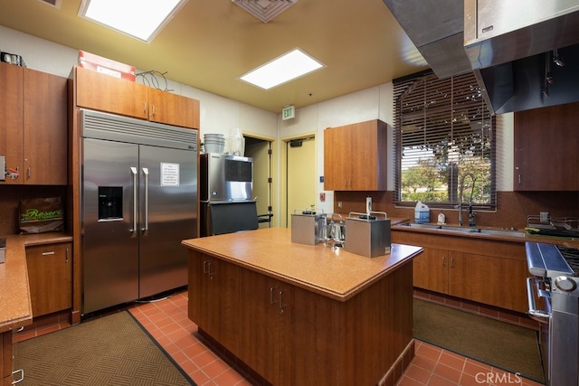 kitchen featuring sink, tile patterned flooring, decorative backsplash, a kitchen island, and high end appliances