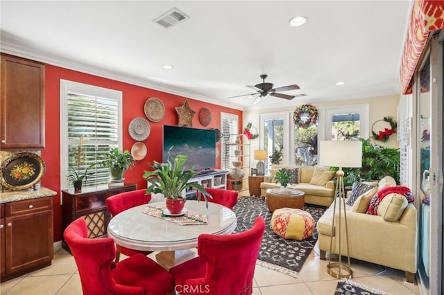 tiled dining space with ceiling fan and ornamental molding