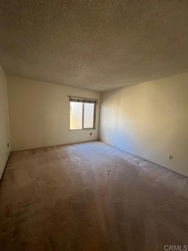 unfurnished room featuring carpet flooring and a textured ceiling