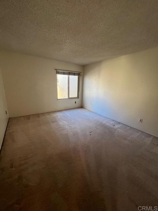 carpeted empty room featuring a textured ceiling