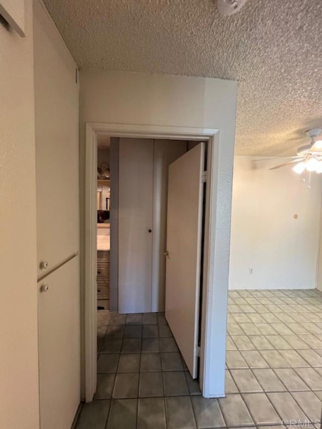 hall featuring tile patterned flooring and a textured ceiling