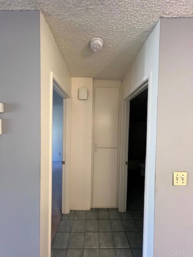 hall featuring a textured ceiling and tile patterned floors