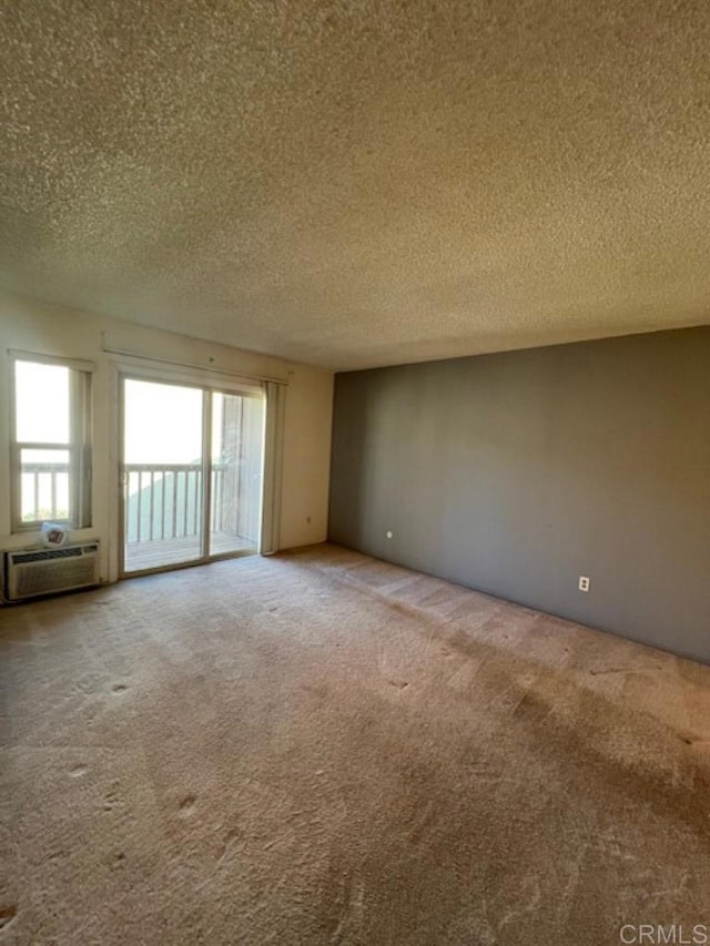 carpeted empty room featuring a wall unit AC and a textured ceiling