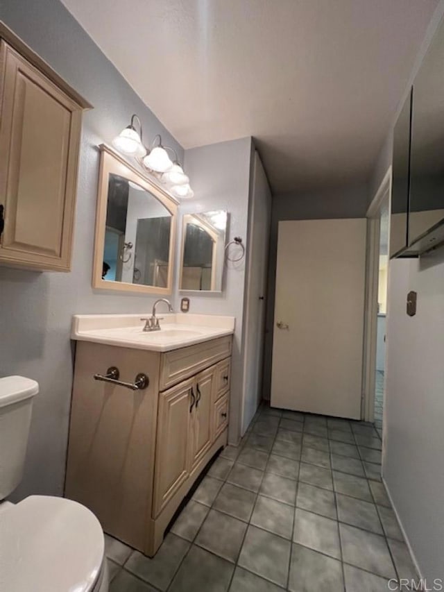 bathroom with toilet, tile patterned floors, and vanity