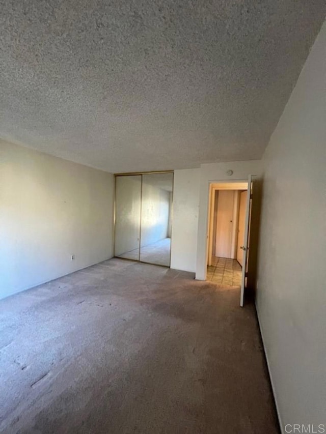 unfurnished bedroom featuring a textured ceiling, a closet, and carpet