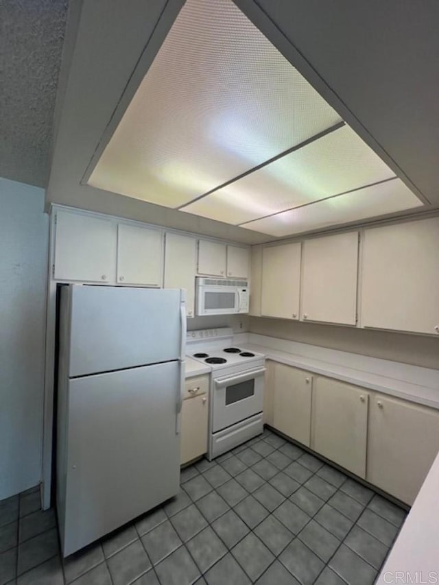 kitchen featuring light tile patterned floors, white appliances, light countertops, and white cabinets