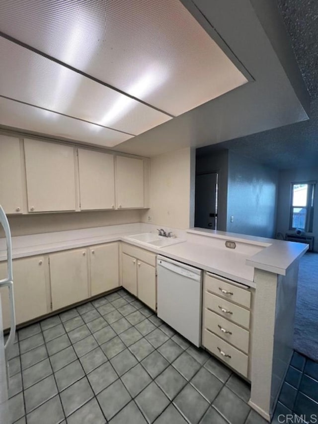 kitchen featuring dishwasher, open floor plan, a peninsula, light countertops, and a sink