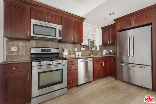 kitchen featuring light stone counters, sink, stainless steel appliances, and light wood-type flooring