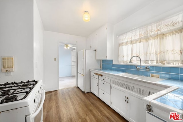 kitchen featuring decorative backsplash, sink, hardwood / wood-style flooring, white cabinetry, and tile counters