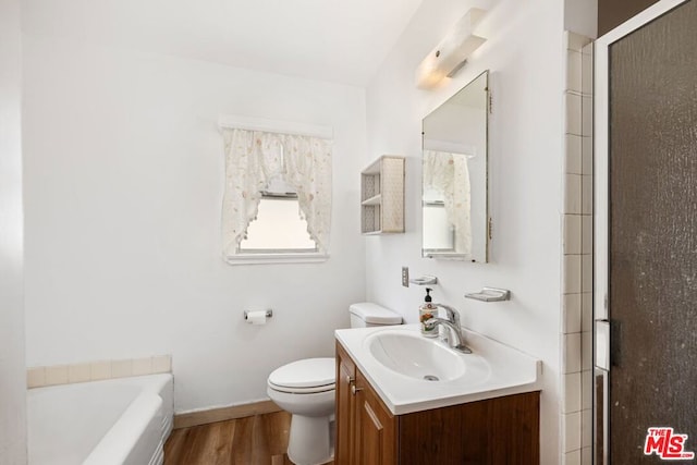 bathroom with hardwood / wood-style floors, vanity, toilet, and a tub