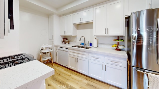 kitchen with dishwasher, sink, stainless steel fridge, white cabinets, and light wood-type flooring