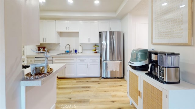 kitchen with white dishwasher, sink, stainless steel fridge, light hardwood / wood-style floors, and white cabinetry