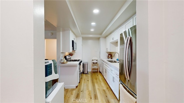 kitchen with white cabinets, appliances with stainless steel finishes, light wood-type flooring, and sink