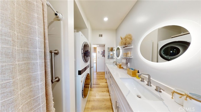 bathroom featuring vanity, wood-type flooring, and stacked washing maching and dryer