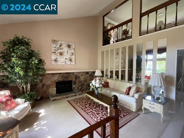 living room with high vaulted ceiling and a stone fireplace