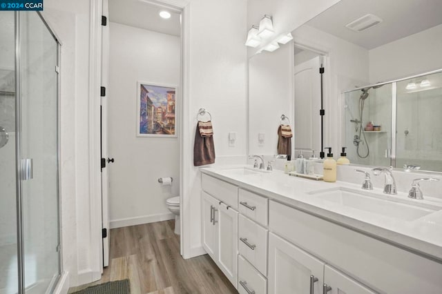 bathroom featuring hardwood / wood-style floors, vanity, a shower with door, and toilet