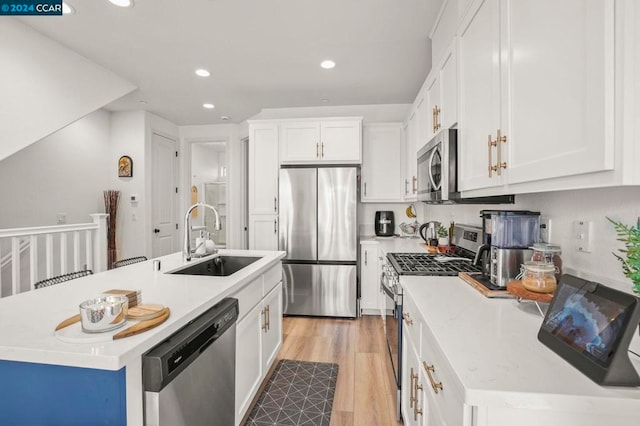 kitchen featuring a kitchen island with sink, white cabinets, sink, light hardwood / wood-style floors, and stainless steel appliances