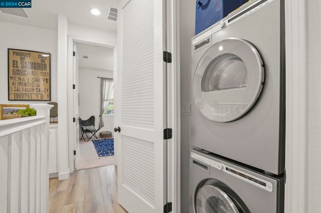 washroom with light hardwood / wood-style floors and stacked washer / drying machine