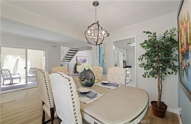 dining space with light hardwood / wood-style floors and a notable chandelier