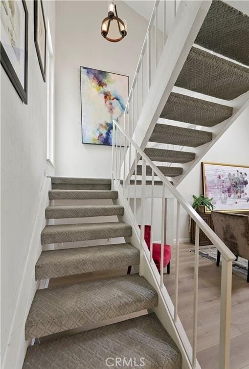 stairway with a chandelier and wood-type flooring