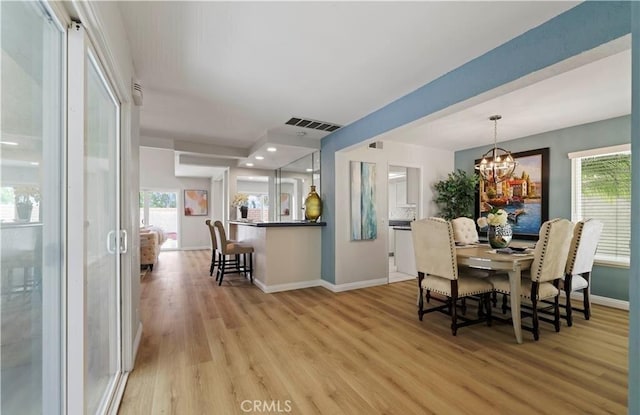 dining room with a chandelier, a wealth of natural light, and light hardwood / wood-style flooring