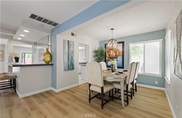 dining area featuring light hardwood / wood-style flooring, plenty of natural light, and a notable chandelier