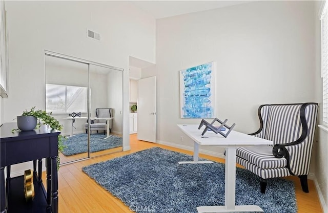 living area with a towering ceiling and hardwood / wood-style flooring