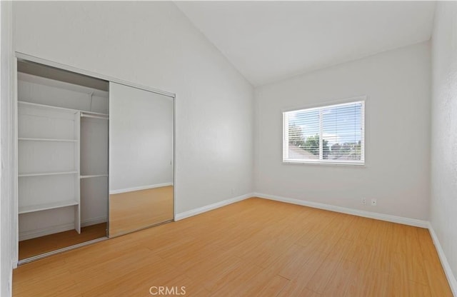 unfurnished bedroom featuring a closet, hardwood / wood-style floors, and vaulted ceiling