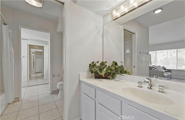 full bathroom with tile patterned floors, shower / bathtub combination with curtain, vanity, and toilet