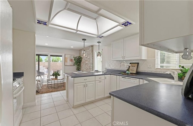 kitchen with kitchen peninsula, white appliances, white cabinets, and sink