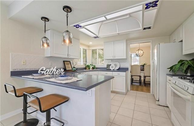 kitchen featuring kitchen peninsula, a kitchen breakfast bar, white cabinetry, and white gas stove