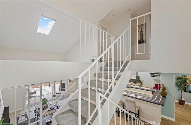 stairway with high vaulted ceiling, a healthy amount of sunlight, and wood-type flooring