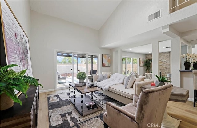 living room with light wood-type flooring and high vaulted ceiling