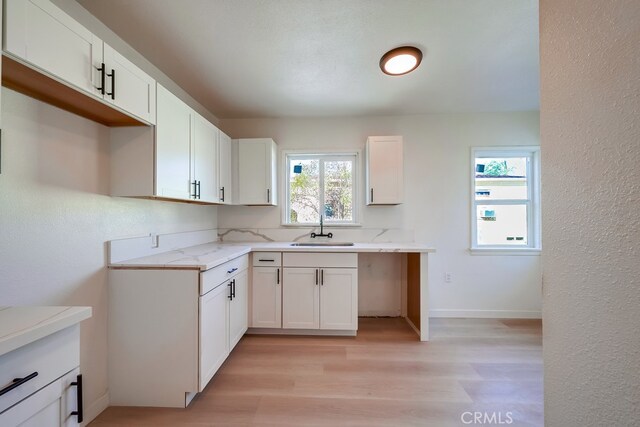 kitchen with light hardwood / wood-style floors, a healthy amount of sunlight, white cabinetry, and sink