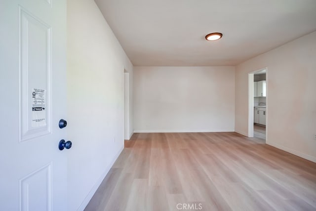 unfurnished room with light wood-style flooring and baseboards