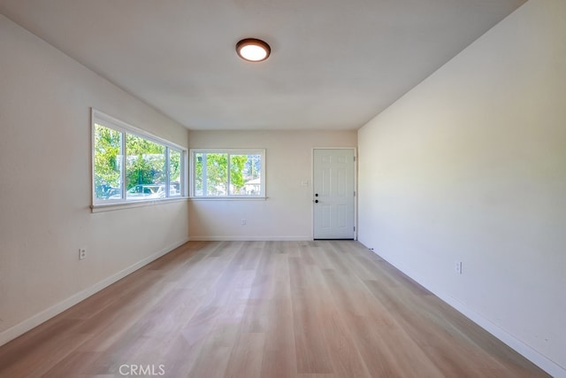 spare room featuring light wood-type flooring and baseboards
