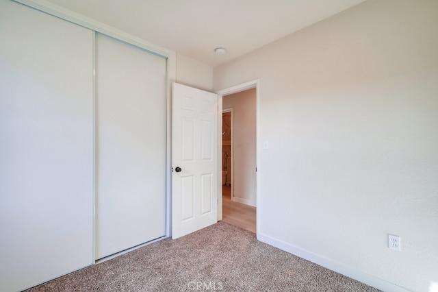 unfurnished bedroom featuring light colored carpet and a closet