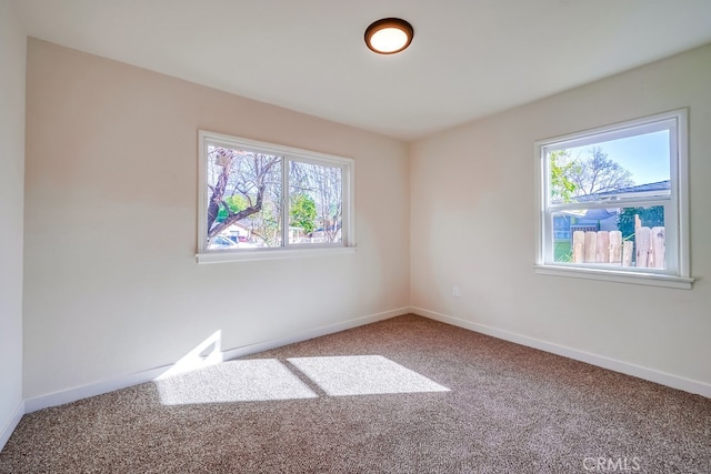 unfurnished room featuring carpet and baseboards