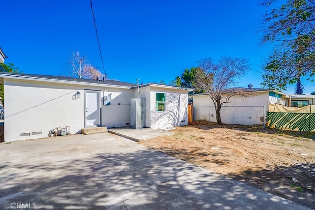 view of front of house featuring crawl space, stucco siding, fence, and a patio