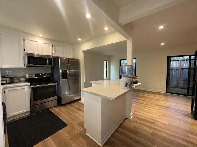 kitchen with white cabinetry, a wealth of natural light, light hardwood / wood-style flooring, decorative backsplash, and appliances with stainless steel finishes