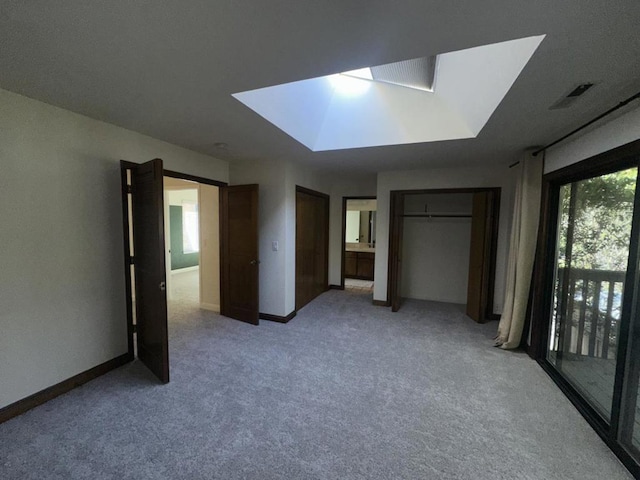 unfurnished bedroom with ensuite bathroom, light colored carpet, and a skylight