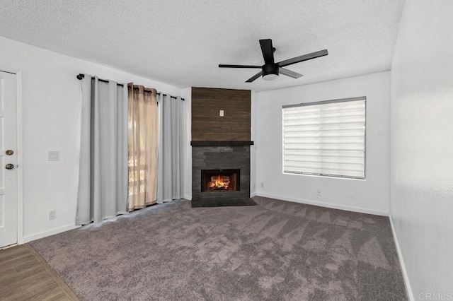 unfurnished living room featuring a textured ceiling, ceiling fan, carpet floors, and a fireplace