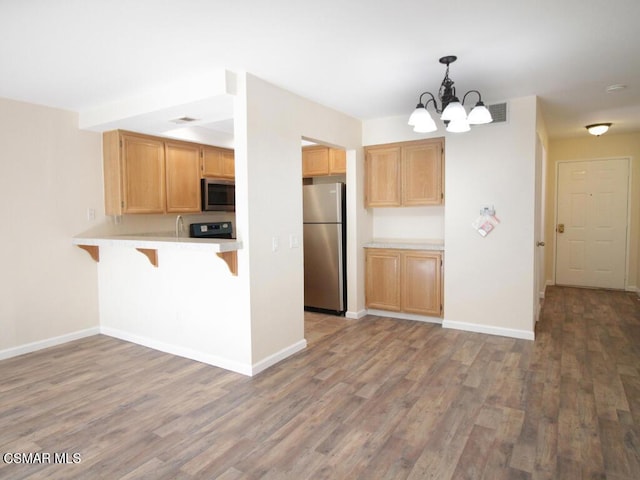 kitchen with hardwood / wood-style floors, kitchen peninsula, stainless steel appliances, and hanging light fixtures