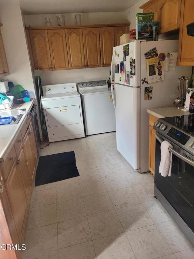 kitchen with stainless steel electric range oven, washer and clothes dryer, exhaust hood, and sink