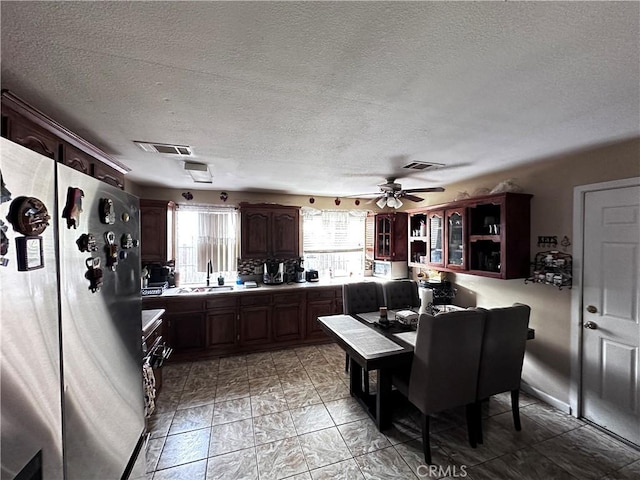 kitchen featuring stainless steel fridge, a textured ceiling, and ceiling fan