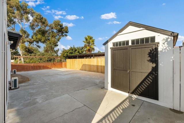 view of patio featuring an outdoor structure, a fenced backyard, and a storage shed