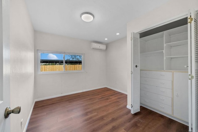 unfurnished bedroom featuring recessed lighting, baseboards, an AC wall unit, and wood finished floors