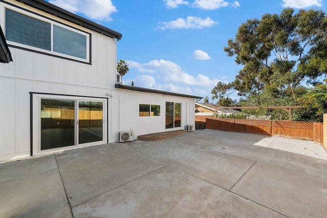 rear view of property with a patio area, ac unit, fence, and board and batten siding