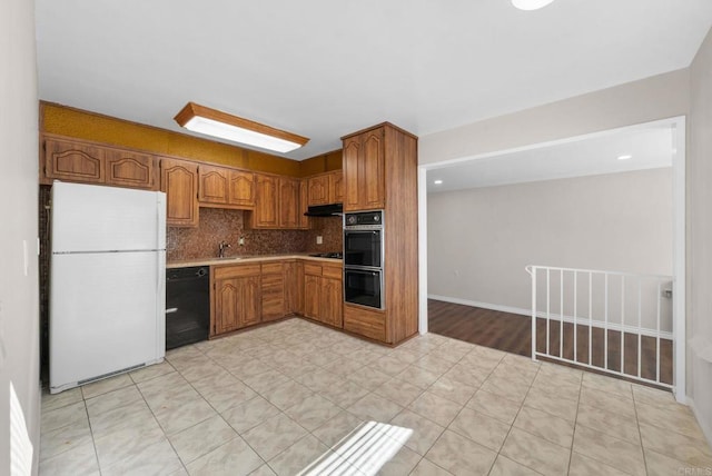 kitchen with under cabinet range hood, light countertops, decorative backsplash, brown cabinets, and black appliances