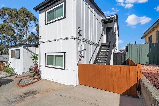 view of side of property with a patio area, stairway, and fence